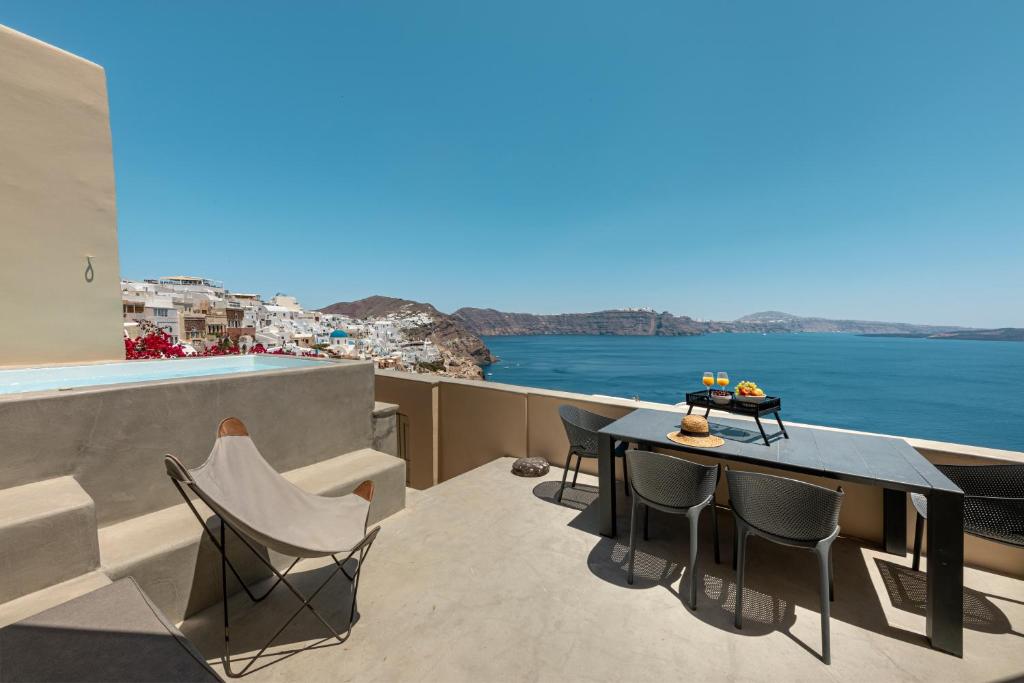 a balcony with a table and chairs overlooking the water at Caldera Houses Oia in Oia