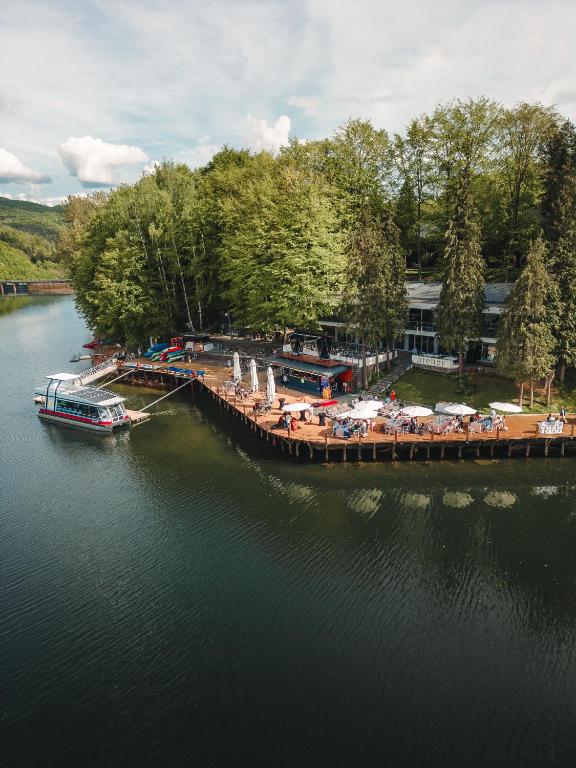 una barca è attraccata a un molo con sedie e ombrelloni di Adventure Lake Resort - Simared a Baia Mare