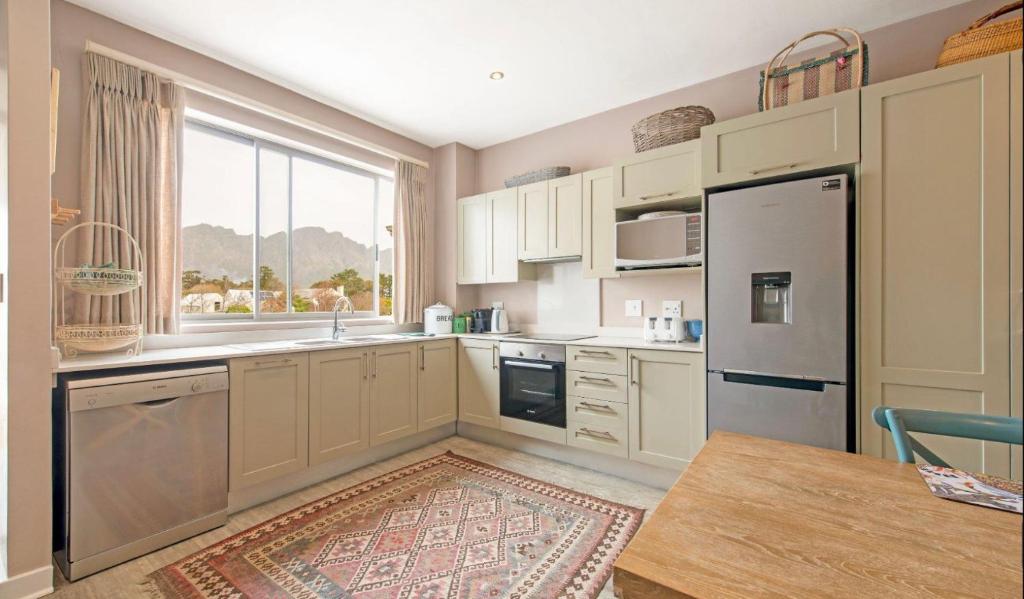 a kitchen with white cabinets and a large window at Le Bourgette in Franschhoek