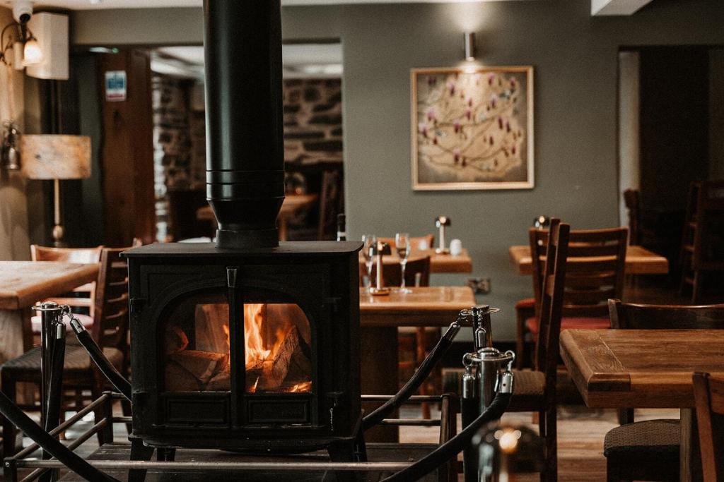 a fireplace in a restaurant with tables and chairs at The Wilson Arms in Torver