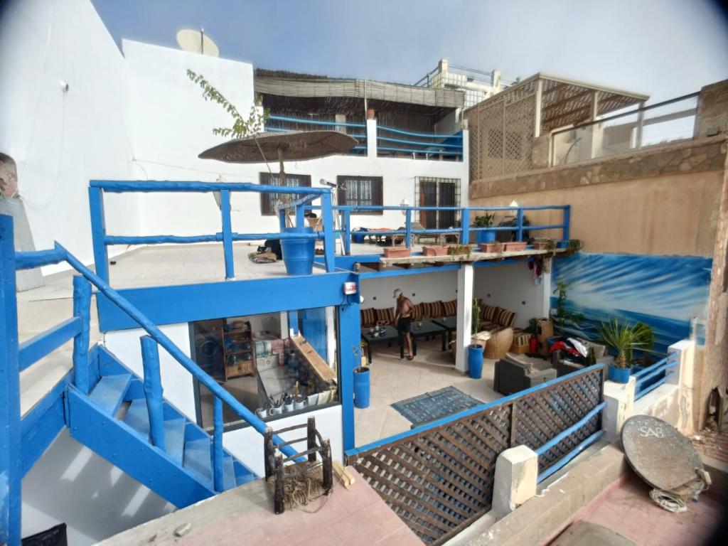 a building with blue stairs and an umbrella at Hostel The Endless House Anchor point in Taghazout