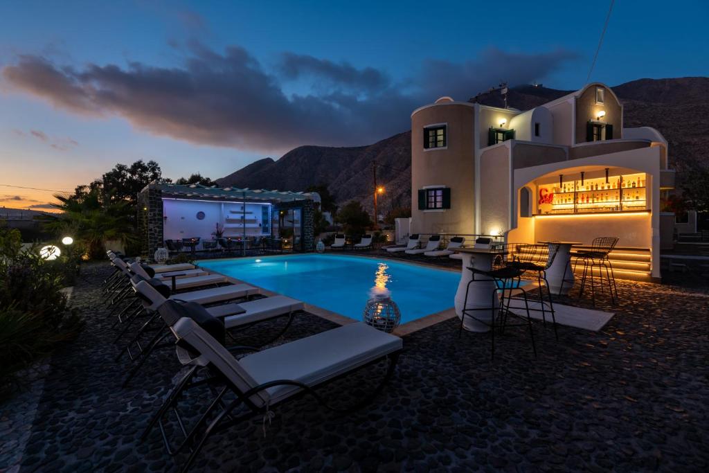 a resort with a pool and lounge chairs at night at Villa Anemomilos Perissa in Perissa