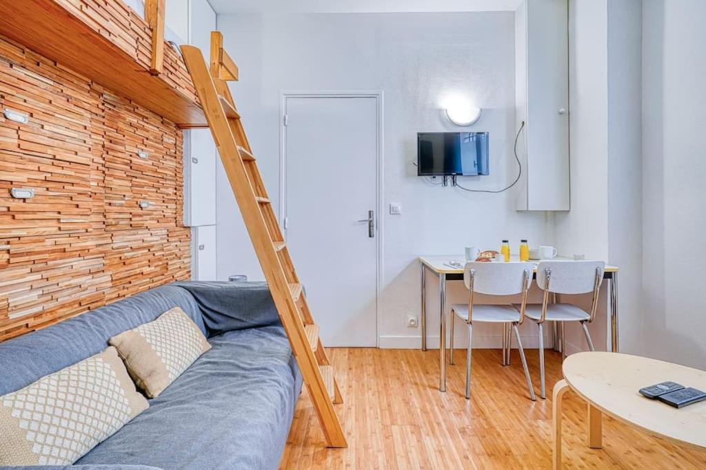 een woonkamer met een bank en een tafel met stoelen bij Charmant Studio Boulevard Voltaire in Parijs