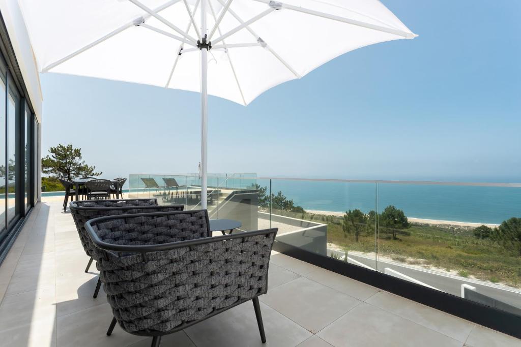 Un balcón con sillas, una sombrilla y el océano. en Casa Berlenga - SCH080, en Famalicão