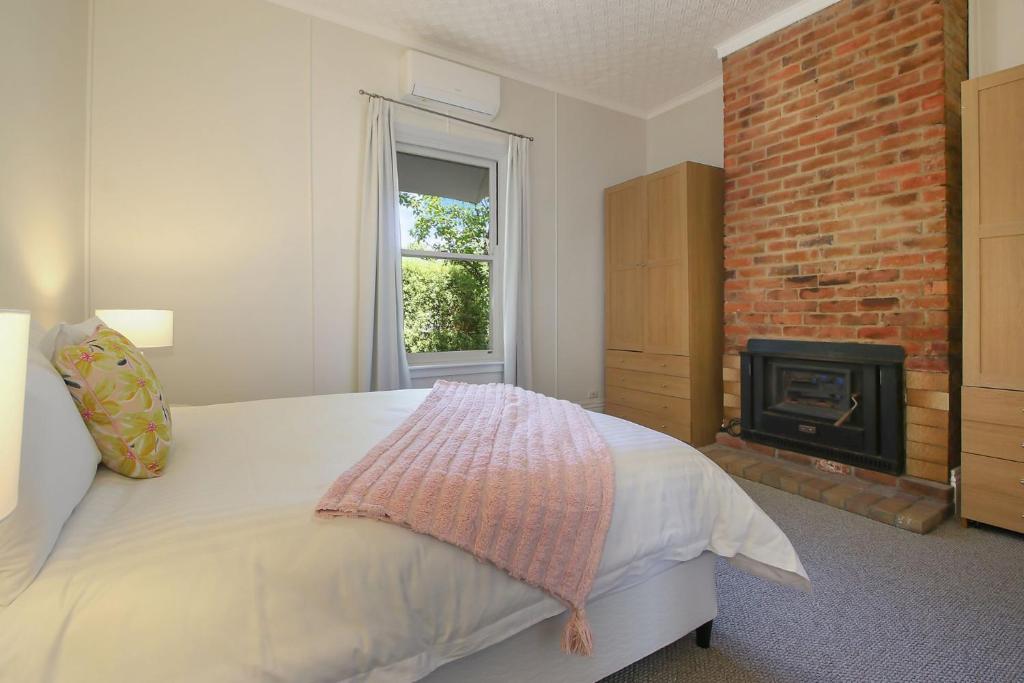 比奇沃斯McNamara House的一间卧室配有一张床和一个砖砌壁炉