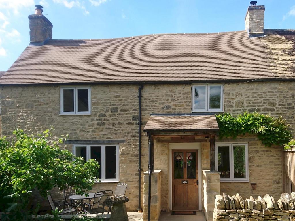 a stone house with a wooden door and a patio at Pass the Keys The Pippins a Cotswold cottage and garden parking in Stow on the Wold