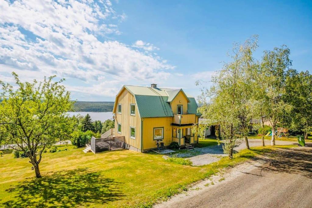 una gran casa amarilla con techo verde en Villa Kakelbont! en Föllinge