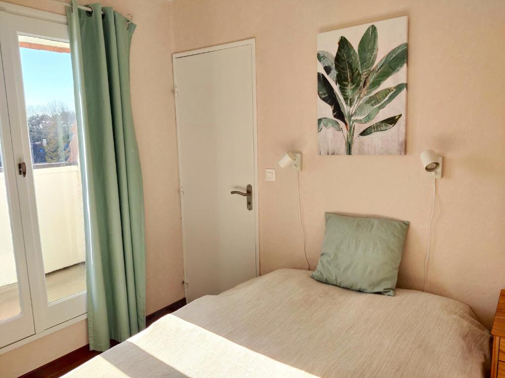 una piccola camera con letto e finestra di Bel appartement refait à neuf, calme et ensoleillé a Cabourg