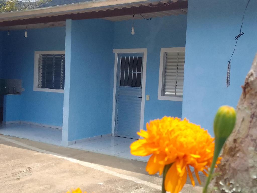 una casa azul con una flor amarilla delante de ella en Suíte Canto Caiçara, en Ubatuba