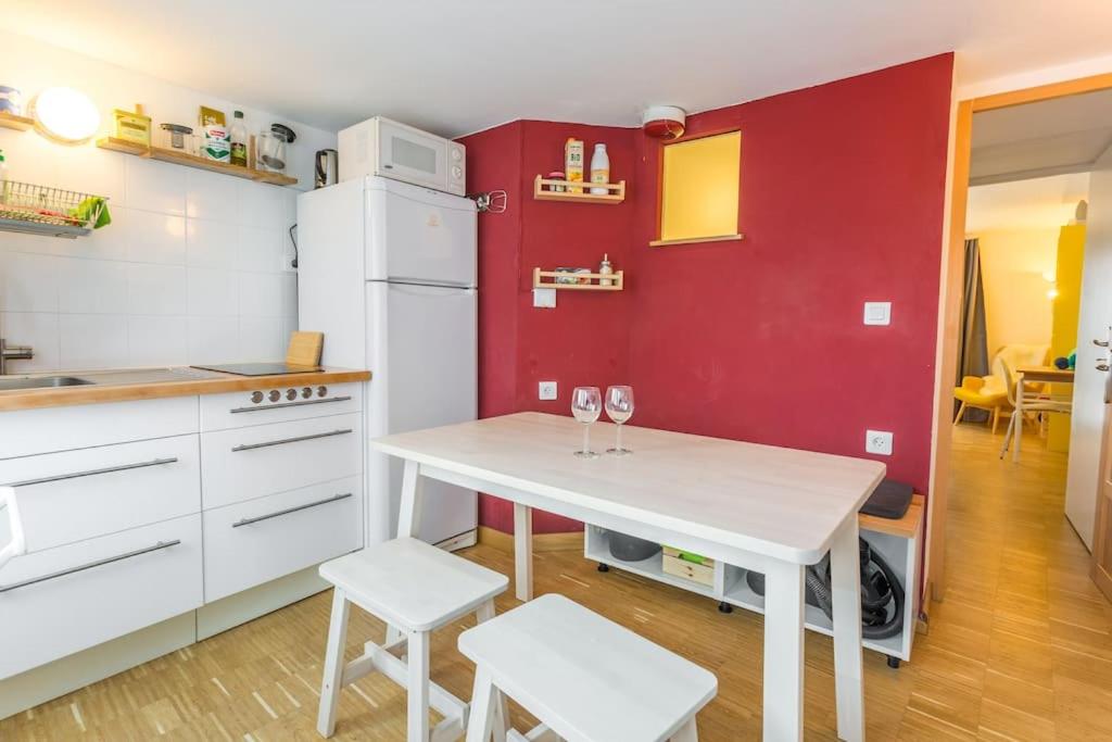une cuisine avec une table blanche et un mur rouge dans l'établissement L'amiénoise-6min à pied du centre, à Amiens