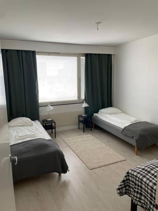 a bedroom with two beds and a window at Kotimaailma - Valoisa kaksio Tikkurilan tuntumassa in Vantaa
