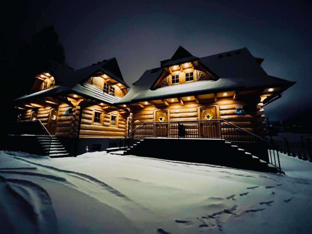 a log cabin in the snow at night at Michałowy Sen Domki Zakopane in Zakopane