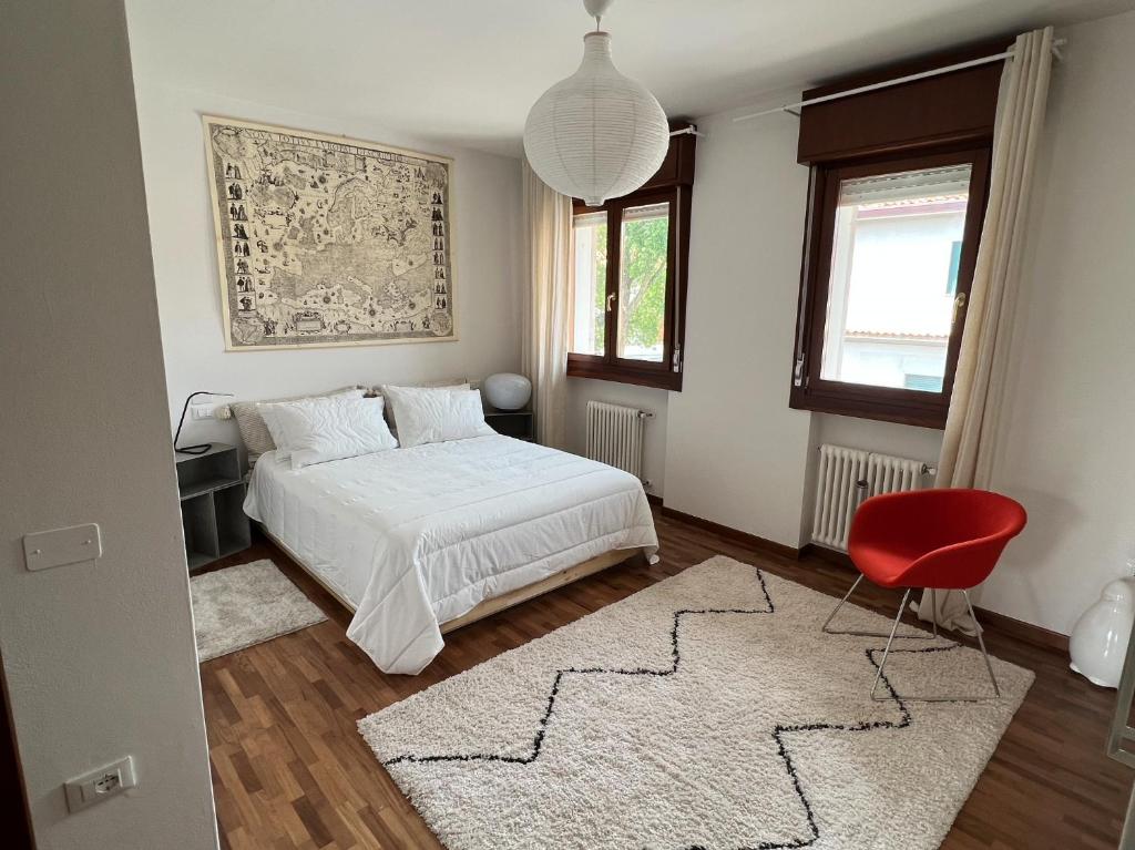 um quarto com uma cama e uma cadeira vermelha em Crestudio Stanza accogliente vicino al Ponte Vecchio em Bassano del Grappa