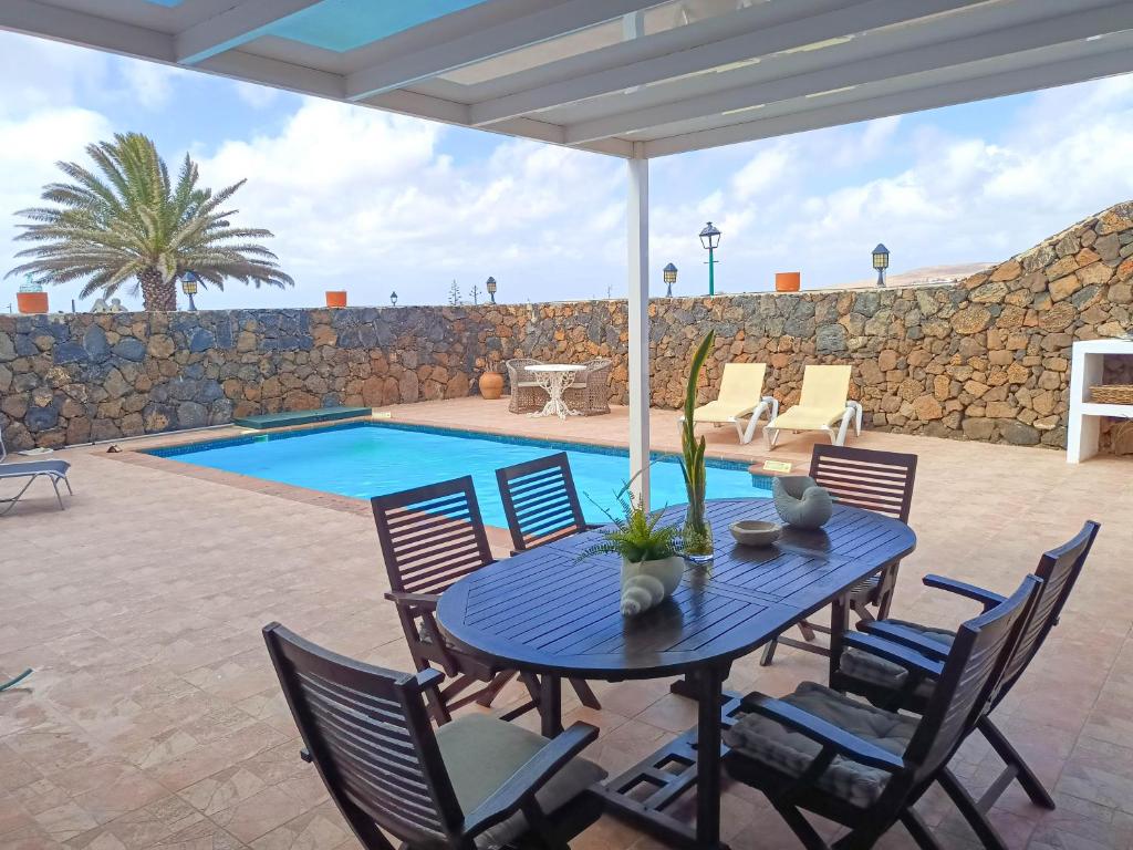 een patio met een tafel en stoelen en een zwembad bij Casa Oasis in Teguise