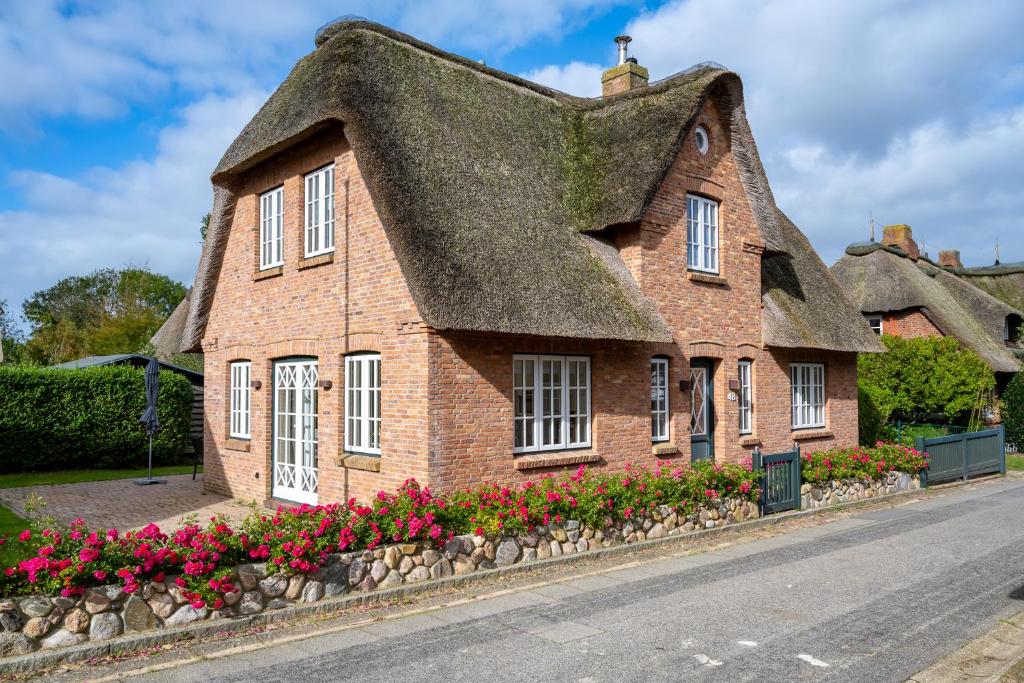 a house with a thatched roof with flowers at Dorftraum in Oevenum