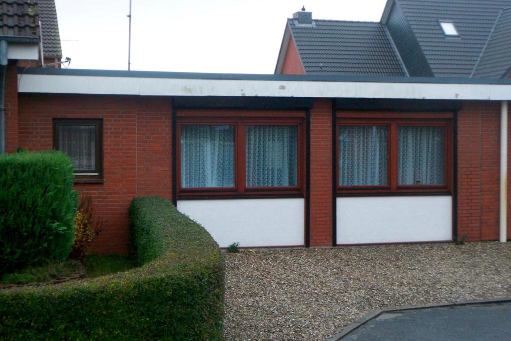 una casa de ladrillo rojo con dos puertas blancas de garaje en Haus Hopp - Bungalow, en Dahme