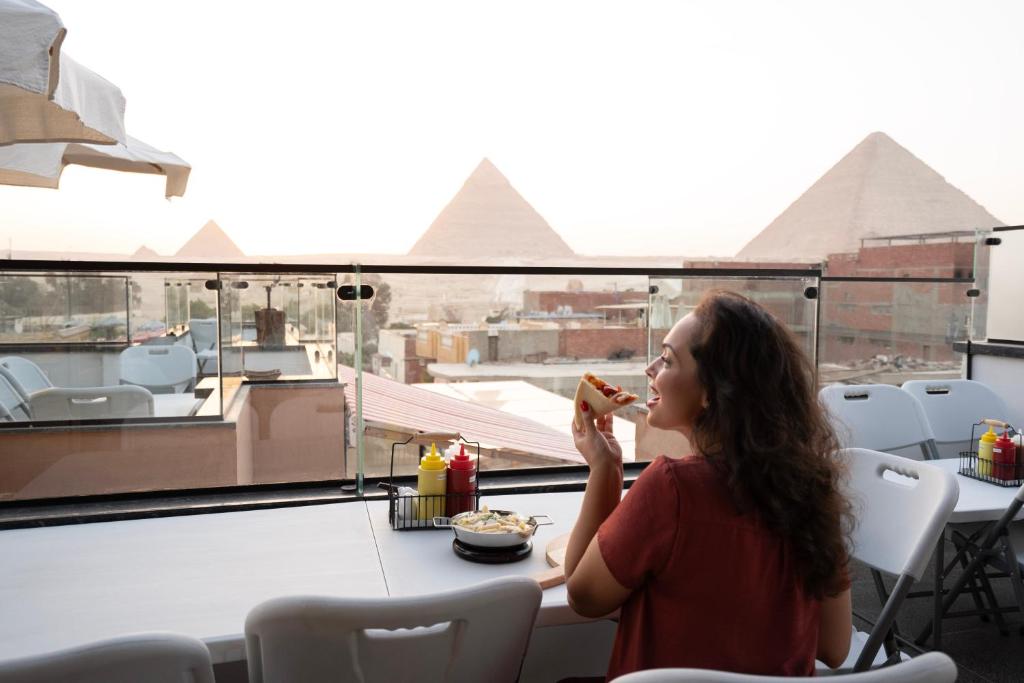 Una donna che mangia un hot dog sul tetto di Sun and Sand Guest House a Il Cairo