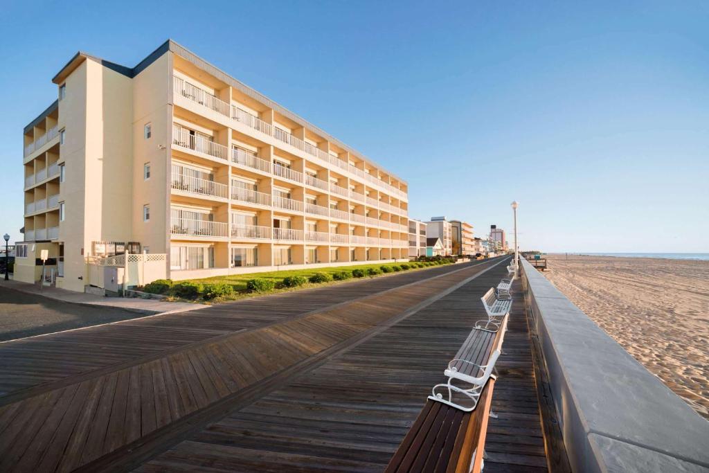 una fila di panchine su una passerella sulla spiaggia di Howard Johnson by Wyndham Ocean City Oceanfront a Ocean City