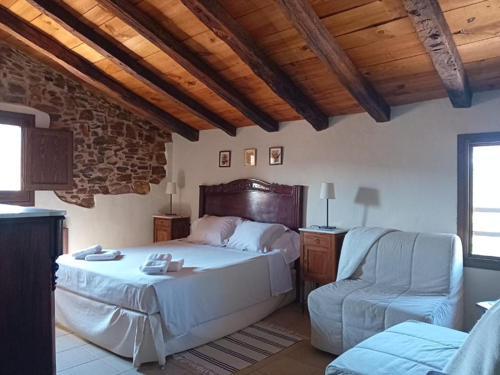 ein Schlafzimmer mit einem Bett und einem Stuhl in der Unterkunft Mas Regort in Vallfogona de Ripolles
