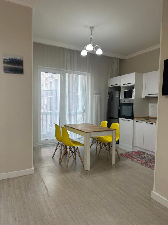 eine Küche und ein Esszimmer mit einem Tisch und gelben Stühlen in der Unterkunft 4YOU апартаменты in Almaty