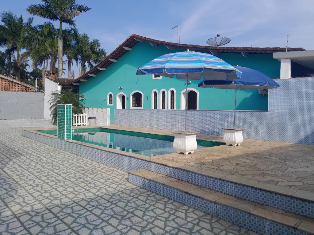 uma casa azul com piscina e dois guarda-sóis em Itanhaem - Casa com Piscina em Itanhaém