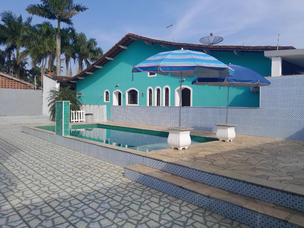 a blue house with a pool and two umbrellas at Itanhaem - Casa com Piscina in Itanhaém