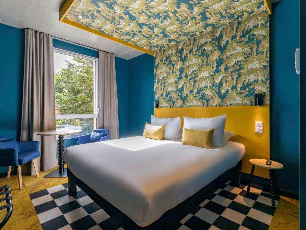 1 dormitorio con 1 cama grande y paredes azules en ibis Styles Dijon Sud Domaine De Beauregard 21600 Longvic en Dijon