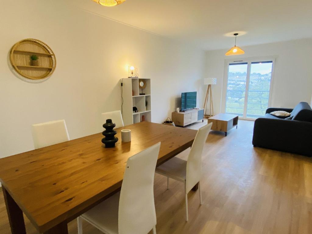 een eetkamer en een woonkamer met een houten tafel en stoelen bij Le haut layoule in Rodez