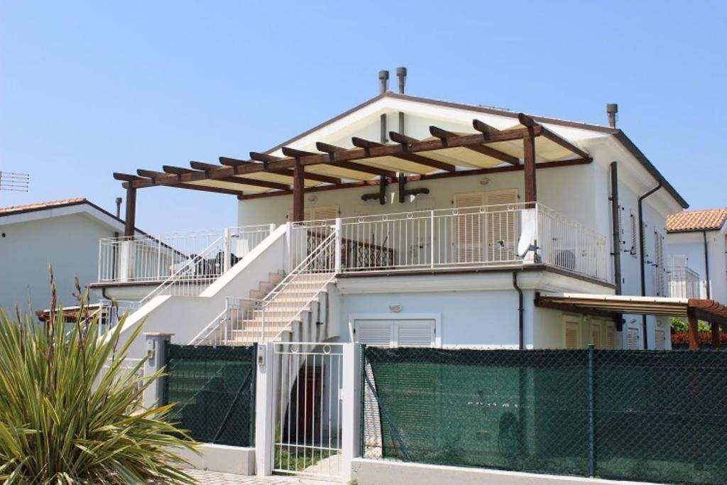 a white house with a balcony and a fence at Appartamenti Mac, trilocali vicino al mare con posto auto in Marcelli