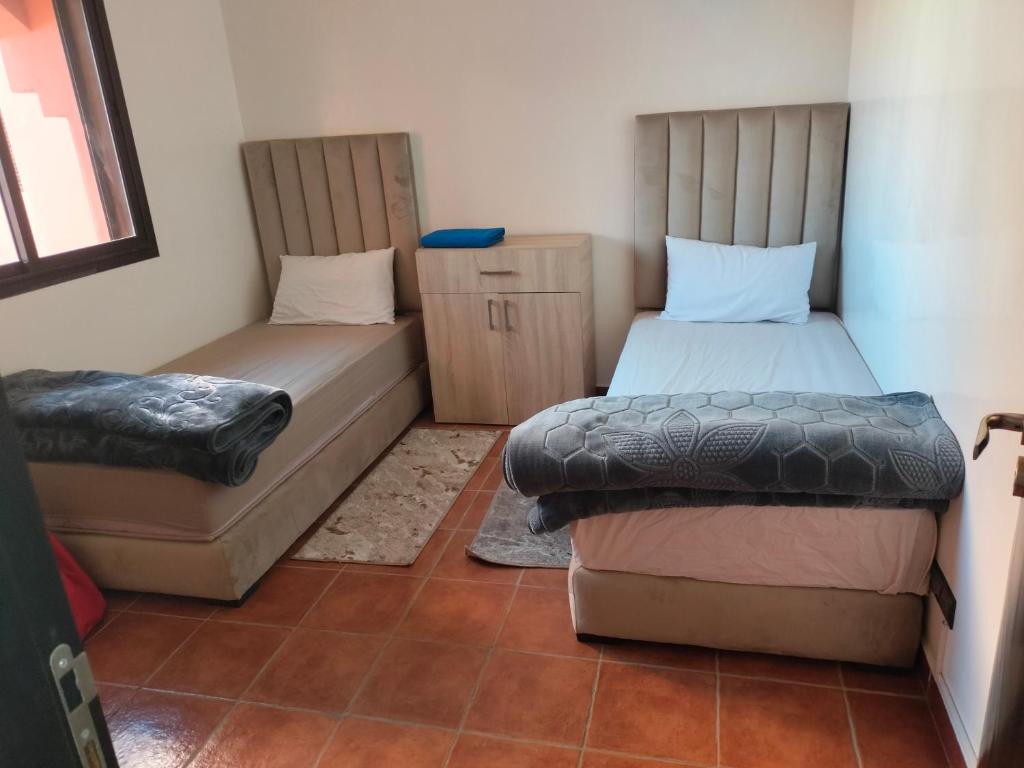 um quarto com duas camas e um repousa-pés em premium village 106 em Marraquexe