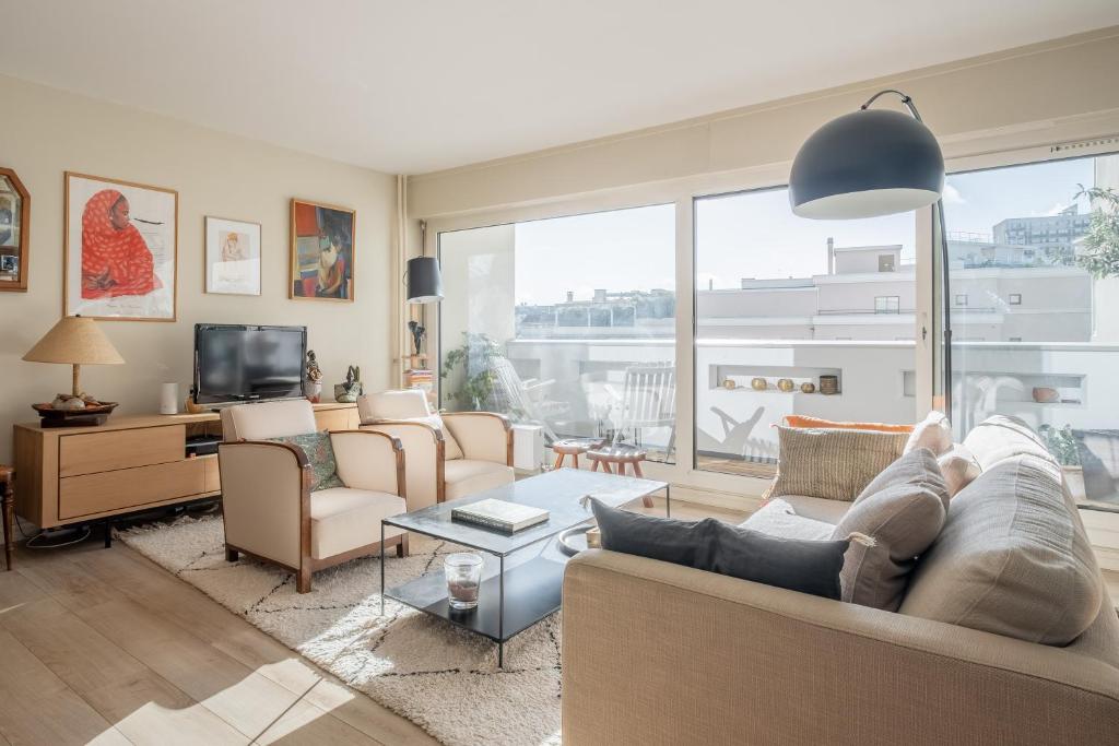 a living room with furniture and a large window at Veeve - Artistic Poise in Boulogne-Billancourt