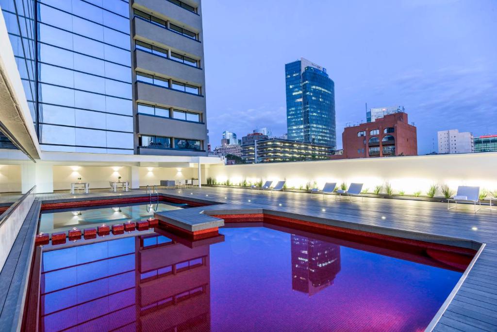 a swimming pool with a city skyline in the background at NH Collection Mexico City Reforma in Mexico City