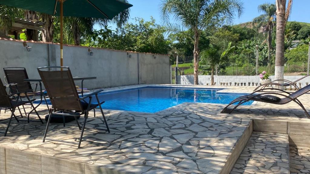 una piscina con sedie, tavolo e ombrellone di Chácara dos Silva a Santa Isabel