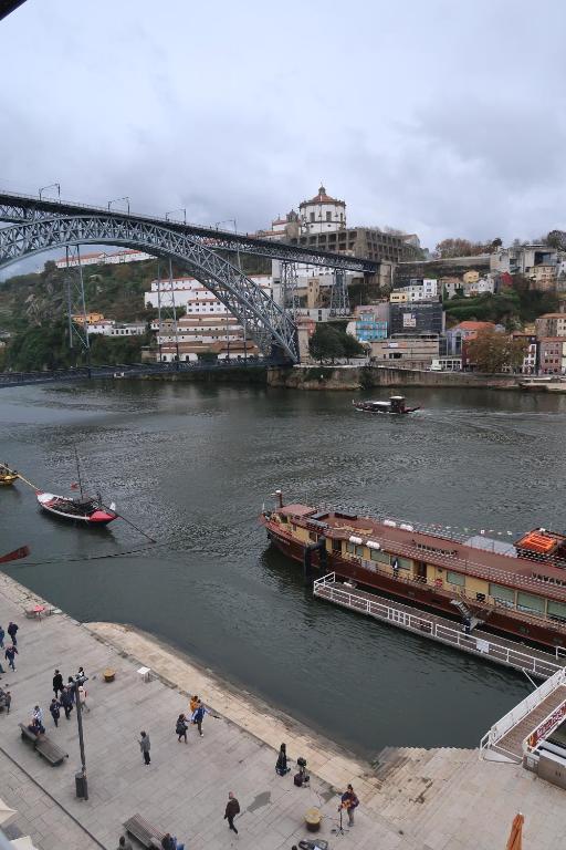 un barco en un río con un puente en el fondo en Apartamentos sobre o Douro, en Oporto