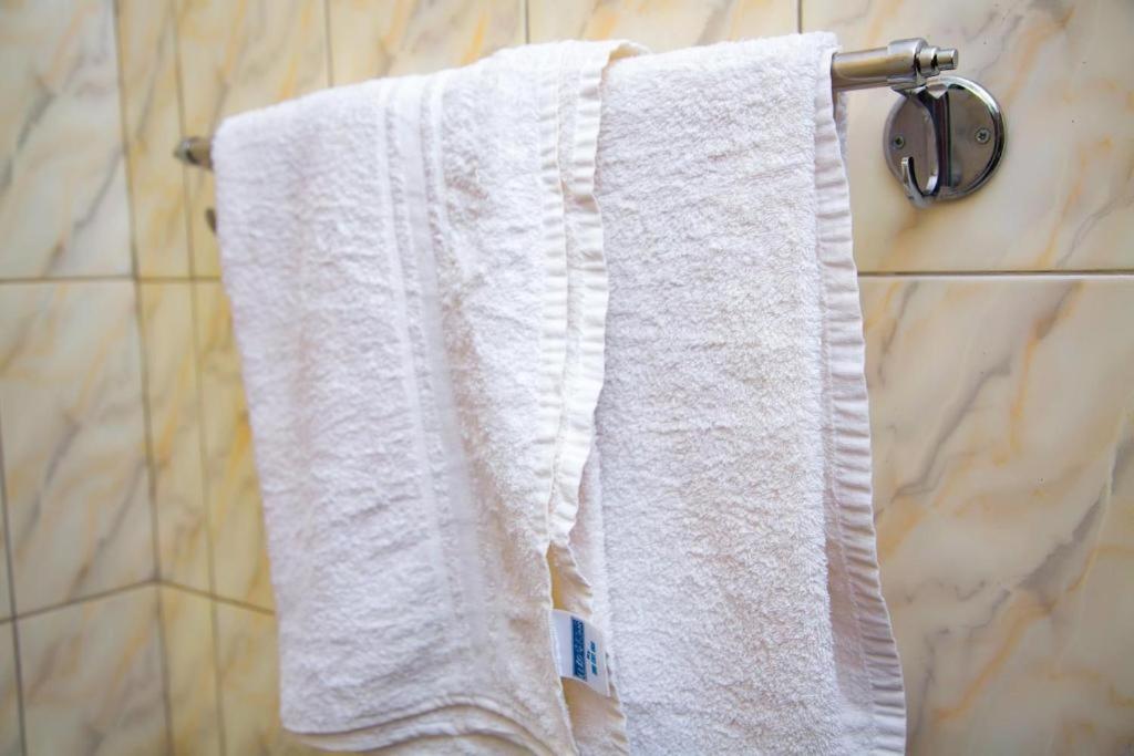 a white towel hanging on a towel rack in a bathroom at Kakiri Gardens and Hotel in Wakiso