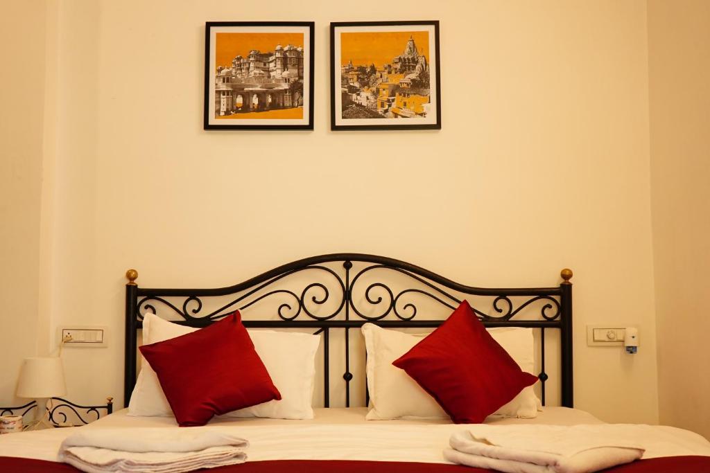 een bed met rode kussens en drie foto's aan de muur bij Rising Shemesh Home Stay in Udaipur