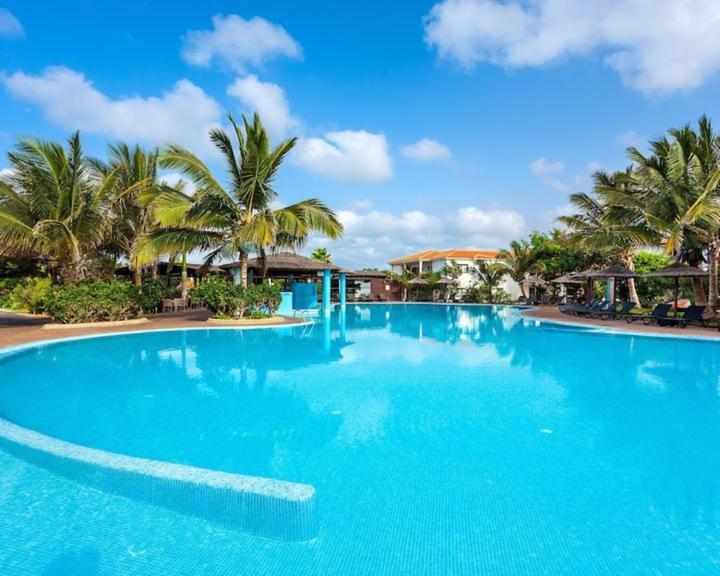a large blue swimming pool with palm trees at Tranquil Apartment at Tortuga Beach - 221 in Prainha