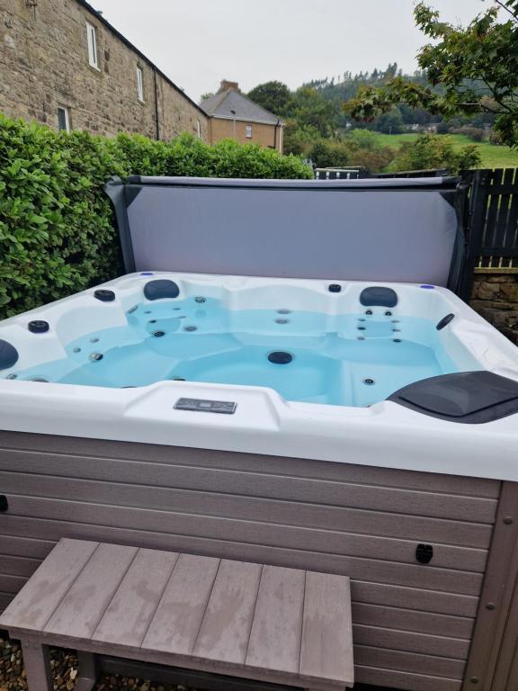 a jacuzzi tub on a patio with a bench at MarMic Cottage in Rothbury