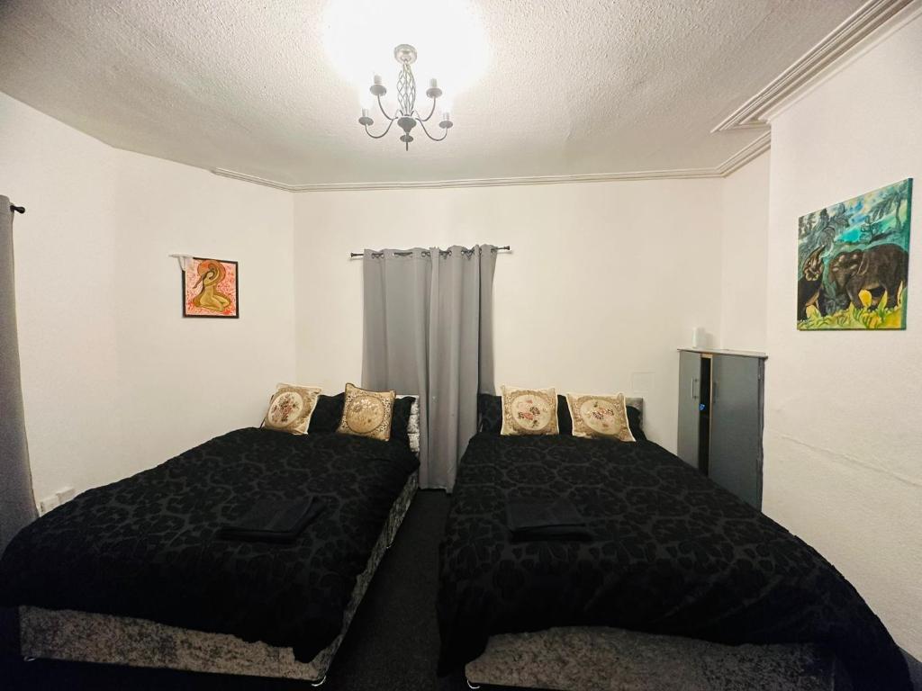 a bedroom with two beds and a chandelier at Samco flat in Ashton in Makerfield