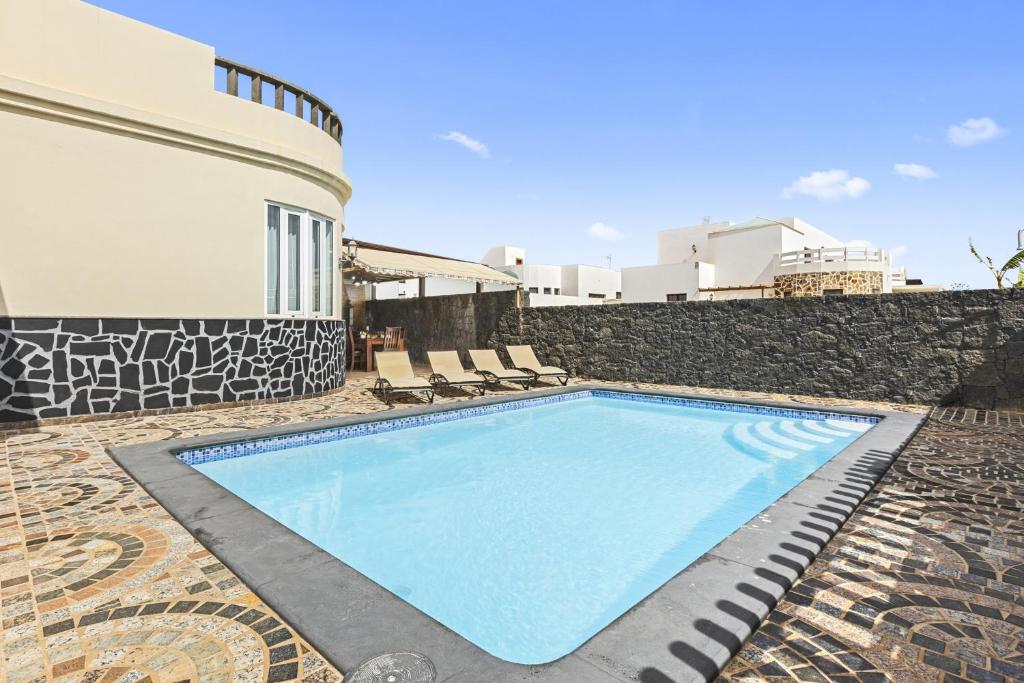 uma piscina com cadeiras e um edifício em Villa Portugal - Villasexperience em Tahiche