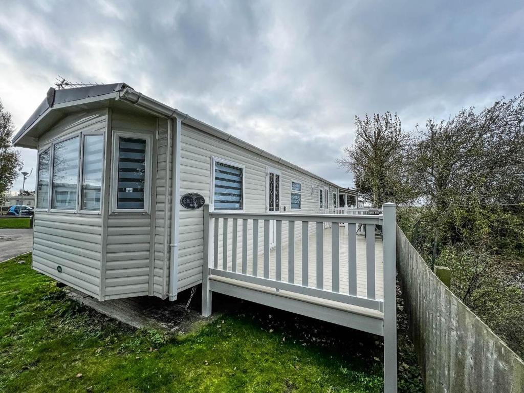 a white mobile home with a white fence at Wonderful 8 Berth Caravan At Seawick Holiday Park In Clacton-on-sea Ref 27077r in Clacton-on-Sea