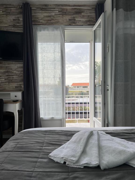 a bedroom with a bed and a large window at Au Petit Bonheur in La Tranche-sur-Mer