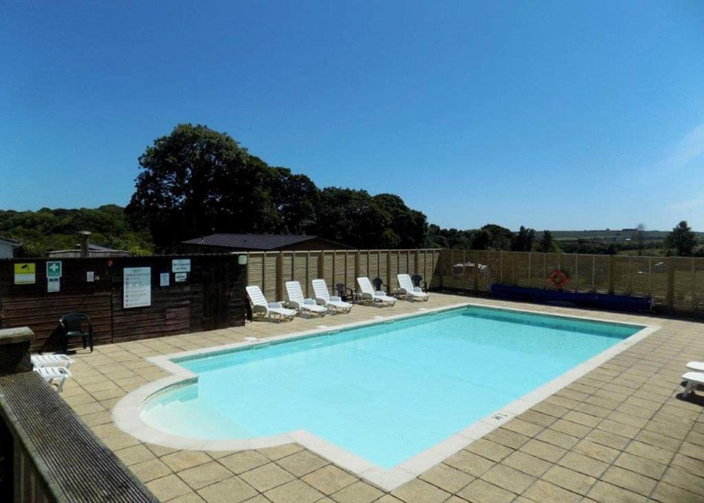 uma grande piscina com espreguiçadeiras em Meadow Lakes Holiday Park em St Austell