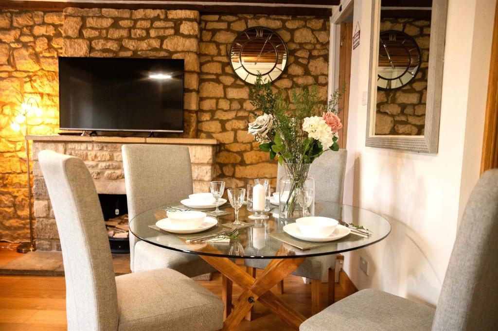 a dining room with a glass table and chairs at 2 Bedroom Charming & Luxury Malt Cottage, Garden, Netflix, Free Parking in Bourton on the Water