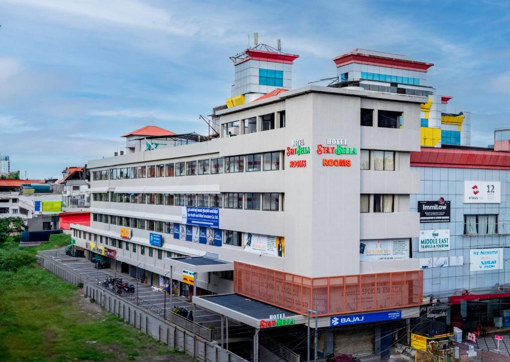 a white building with colorful signs on it at Hotel Stay Bella Kozhikode in Kozhikode