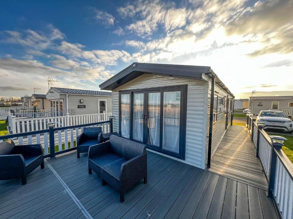 a large deck with chairs and a house at Beautiful 6 Berth Caravan With Decking, Wifi And Field Views Ref 29029sv in Clacton-on-Sea
