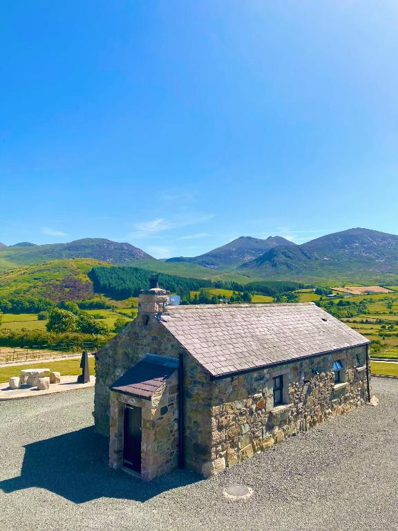 an old stone building with a roof with mountains in the background at Tara’s Hill Cottage in Kilcoo