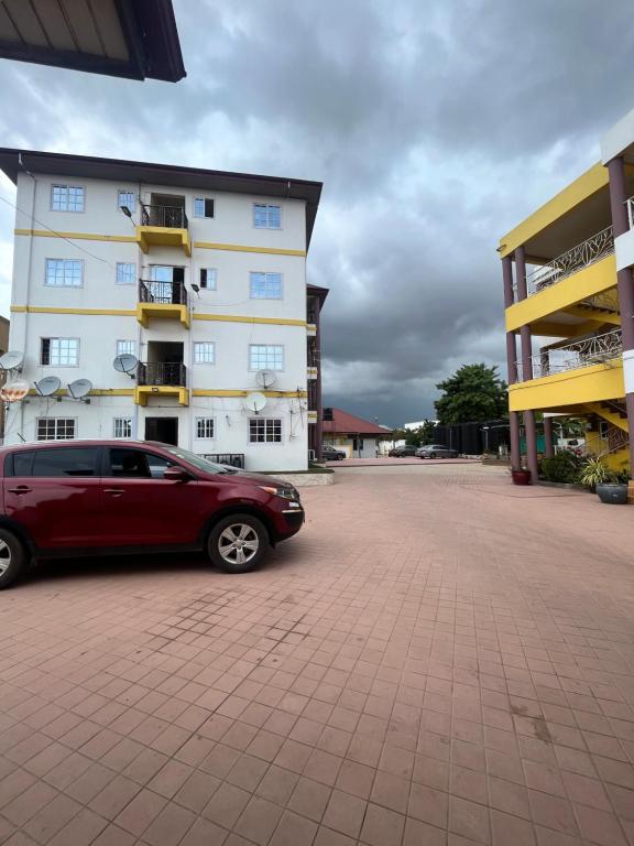 ein rotes Auto, das vor einem Gebäude parkt in der Unterkunft Taari's Place in Accra