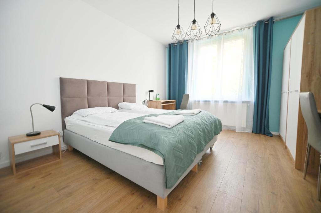 - une chambre avec un grand lit et des rideaux bleus dans l'établissement Victus Apartamenty, Apartament Rey, à Sopot