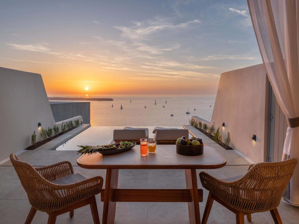 a table on a balcony with a view of the ocean at Santo Mine Oia Suites in Oia